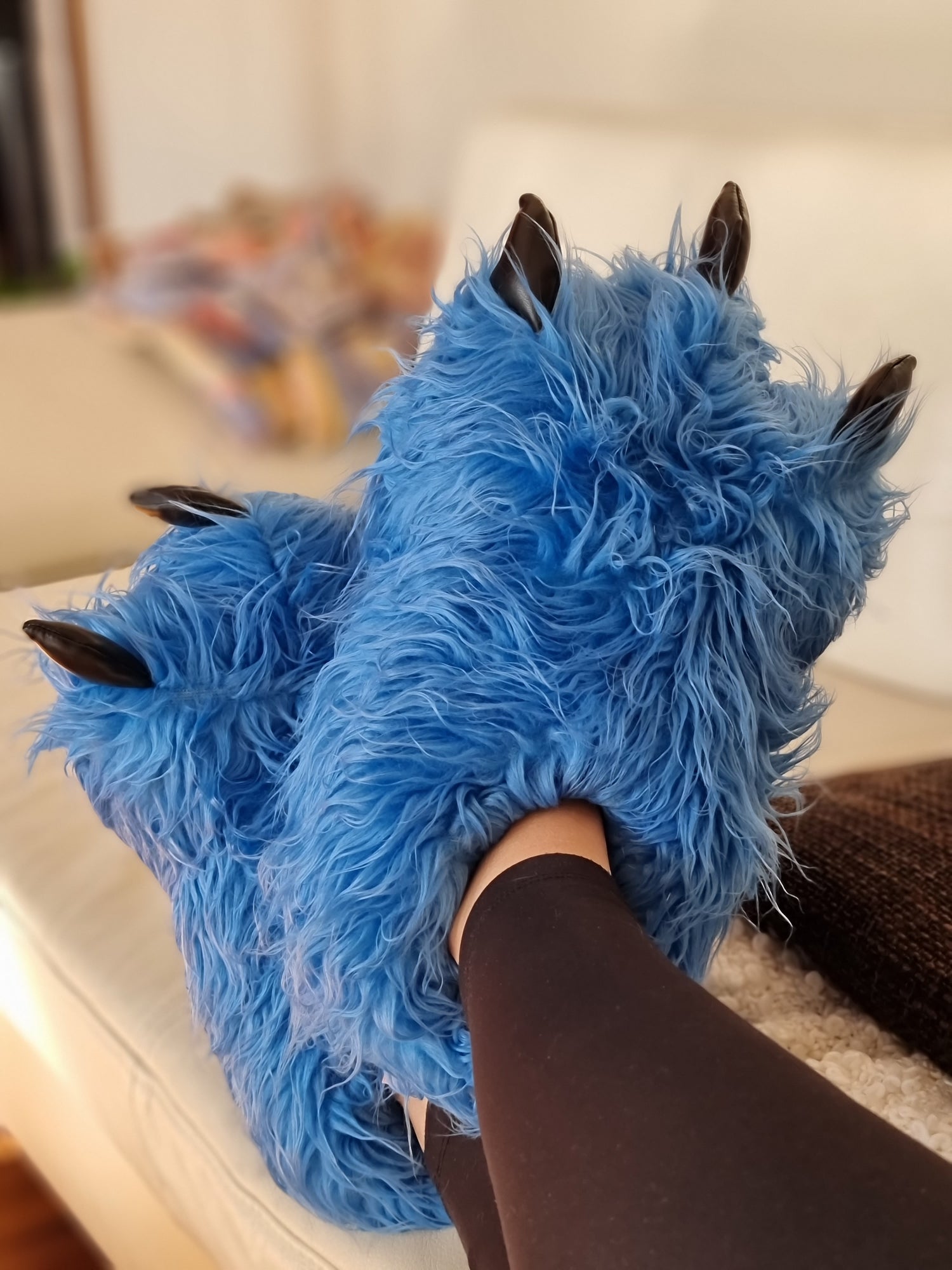 Person mit funslippers blauen Tatzenhausschuhen liegt auf Couch