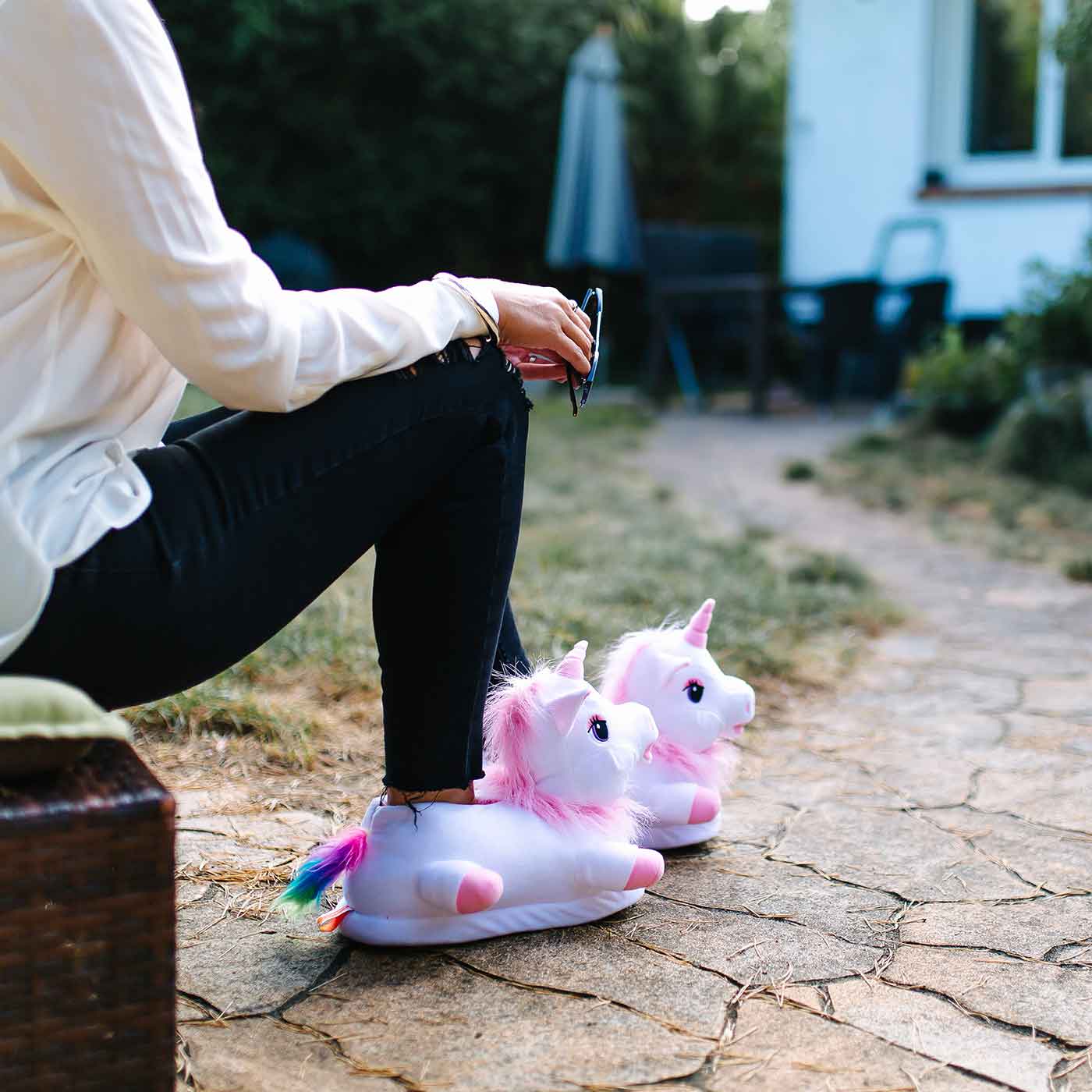 Sitzende Person trägt Einhornhausschuhe in pink-weiss